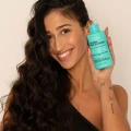 usmiechnietamodelkatrzymajacawdloniSzampon_Maska-NaturalFrizzControl_Przeciwpuszeniusie_Wygladzenien_4.webp